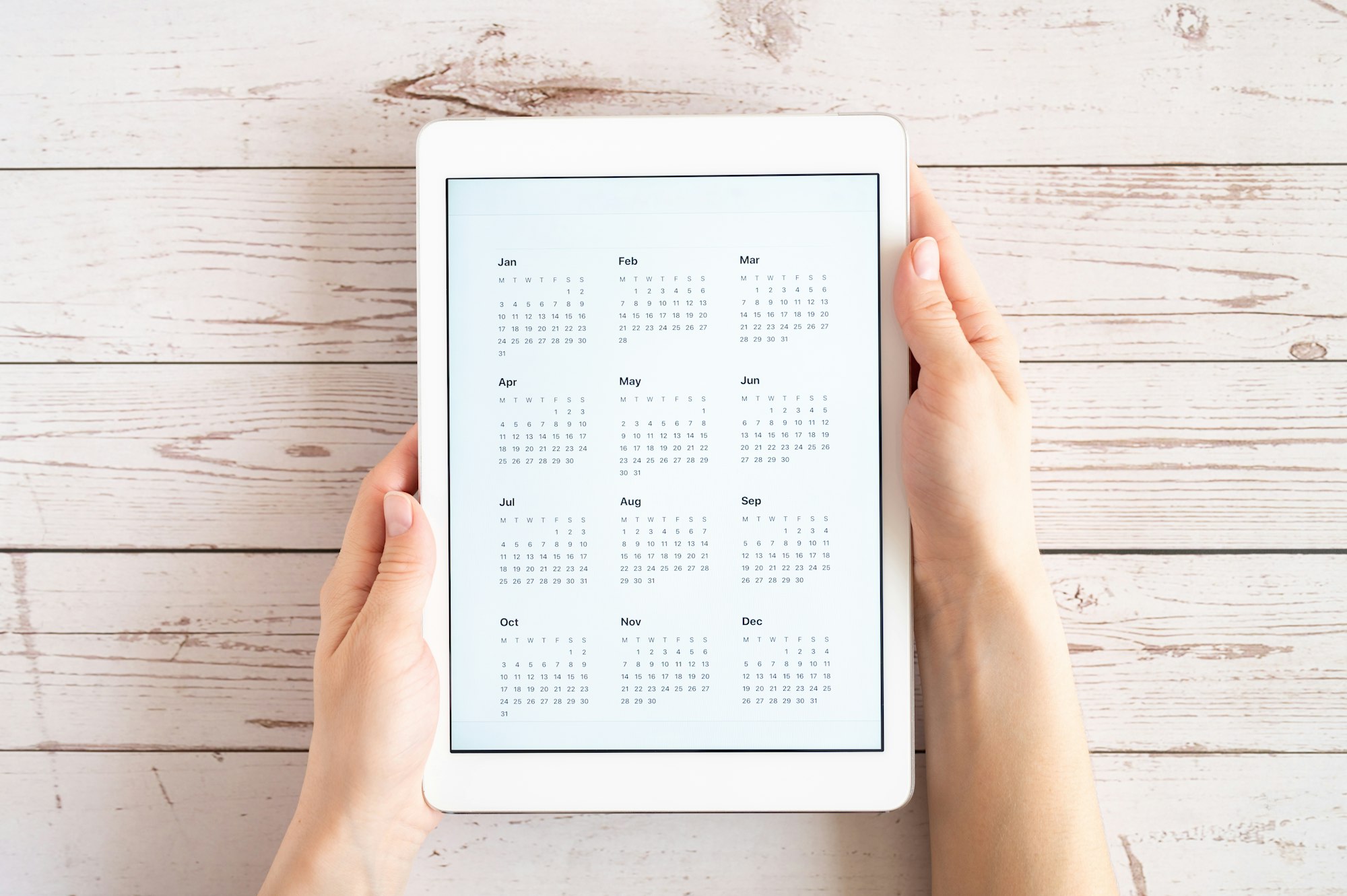 woman's hands holding tablet with calendar for unspecified unknown date year without date flat lay
